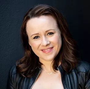 Headshot of Lizzie O'Shea. She has her head cocked slightly to one side, with a slight smile. She has dark shoulder-length hair, She's wearing a leather jacket.l